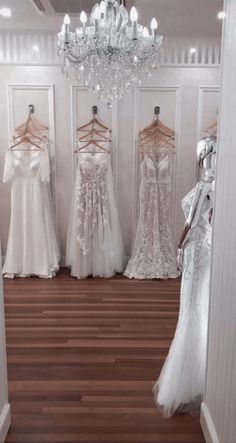 wedding gowns are on display in a white room