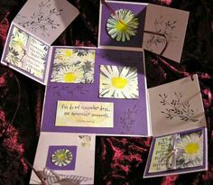 some cards with flowers and words on them sitting on a purple cloth covered tablecloth