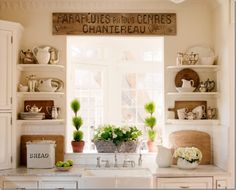 a kitchen with white cabinets and green plants