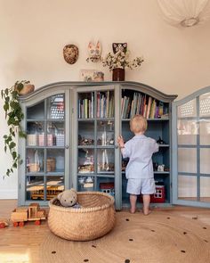 a little boy standing in front of a book shelf