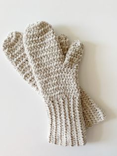 a pair of white knitted mittens sitting on top of a white countertop