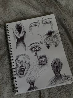 a notebook with sketches of people's faces and hands on top of a blanket