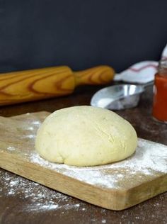 a doughnut sitting on top of a wooden cutting board next to a rolling pin