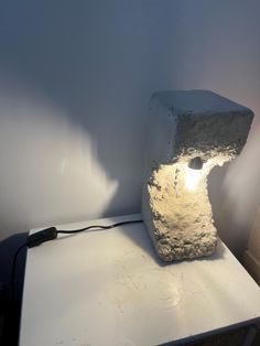 a stone lamp sitting on top of a white table next to a light bulb in the corner