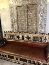 an ornate wooden bench sitting in front of a wall with two large mirrors on it's sides