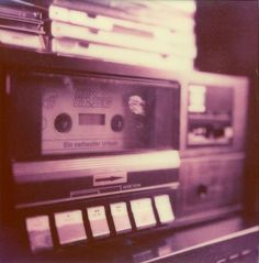 an old fashioned cassette player sitting on top of a table next to a shelf filled with cds