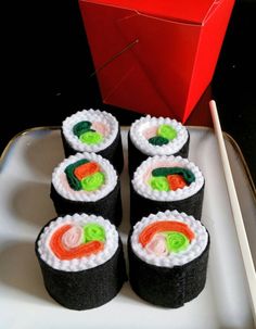 four sushi rolls on a plate with chopsticks next to it and a red box in the background