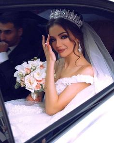 a bride sitting in the back seat of a car with her hand up to her face