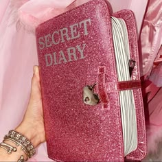 a pink book with the words secret diary on it is held by a woman's hand