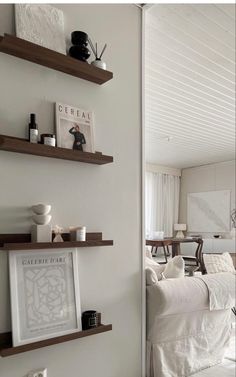 a living room filled with white furniture and lots of open shelves above the couches