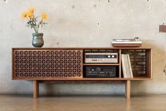 a record player sitting on top of a wooden shelf next to a vase with flowers