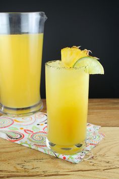 two glasses filled with orange juice and garnished with a slice of pineapple