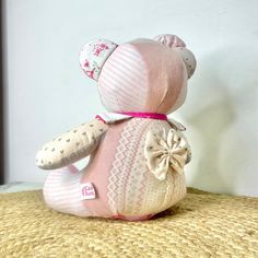 a pink teddy bear sitting on top of a bed next to a white and brown wall