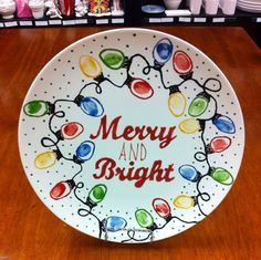 a merry and bright plate with lights on it sitting on top of a wooden table