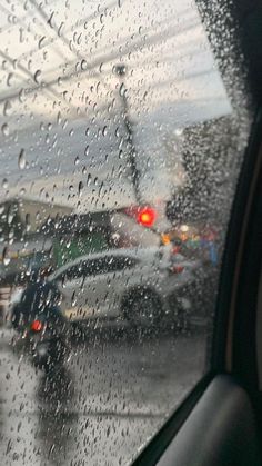 rain drops on the windshield of a car as it drives down a city street with traffic lights