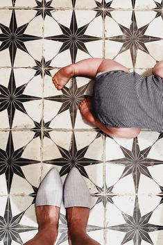 a man laying on top of a tiled floor next to his feet in socks and slippers