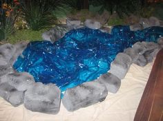 there is an artificial pond made out of rocks and blue water in the middle of it