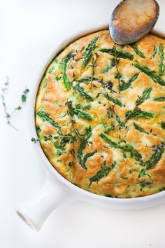 a casserole dish with asparagus on top and a spoon in it