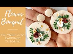 the polymer clay earrings are decorated with flowers and leaves, while being held in someone's hand