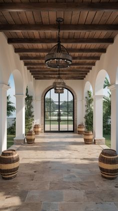 an outdoor area with several wooden barrels on the floor and large doors leading to another room