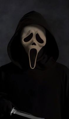 a person in a black hoodie holding a knife and wearing a ghost mask with its mouth open