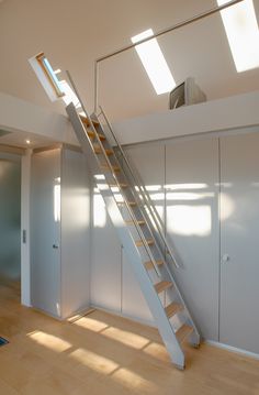 an empty room with stairs leading up to the second floor and skylights above it