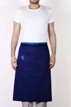 a man in a white shirt and blue skirt is standing with his hands on his hips