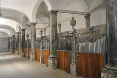 an old building with columns and wooden doors in the center, along with stone pillars on either side