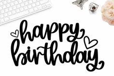 the happy birthday lettering is next to a keyboard, flowers and other items on a desk