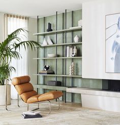 an orange chair sitting in front of a bookshelf filled with vases and plants