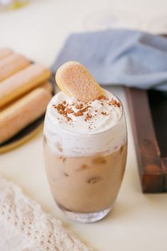 there is a drink with whipped cream and cookies on the table in front of it