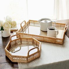 two wicker trays sitting on top of a table next to a vase with flowers