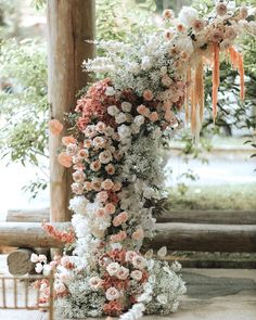 an arrangement of flowers and greenery is arranged on the side of a wooden structure