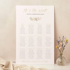 a wedding seating chart next to a vase with flowers