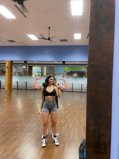 a woman taking a selfie in an empty dance studio with her cell phone up to her ear