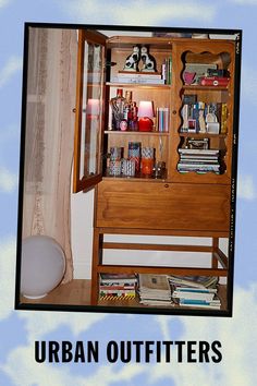 an open book shelf with books and magazines on it, in front of a curtained window