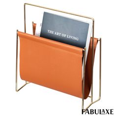 an orange leather magazine holder with a book in it's center and the text, the art of living