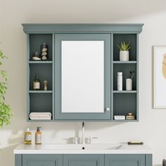 a bathroom vanity with blue cabinets and white counter top, along with a plant in the corner