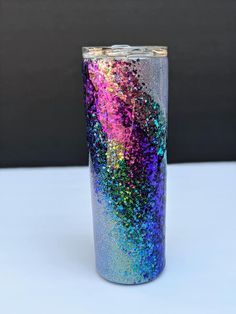 a purple and blue glitter tumbler sitting on top of a table