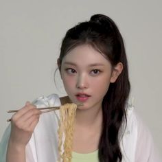 a young woman eating noodles with chopsticks