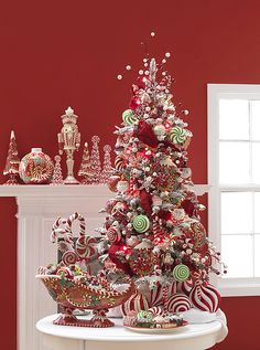 a red christmas tree with candy canes and candies on the table in front of it