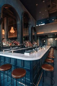 a bar with several stools and bottles on the counter in front of it,