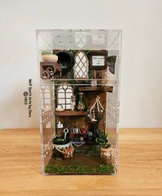 a doll house with lots of windows and plants on the shelf in front of it