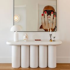 a white table with a large mirror above it and candles on the counter in front of it