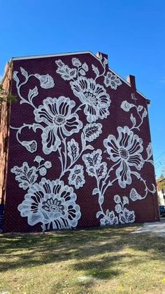 a building painted with white flowers on it's side in the daytime time, against a blue sky