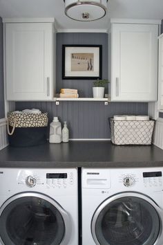 a washer and dryer in a laundry room with white cabinets, gray counter tops