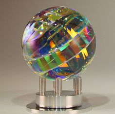 a crystal ball is sitting on top of a metal stand with two silver poles and a gray background