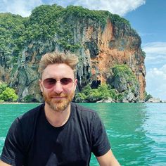 a man sitting on top of a boat in the ocean next to a mountain range