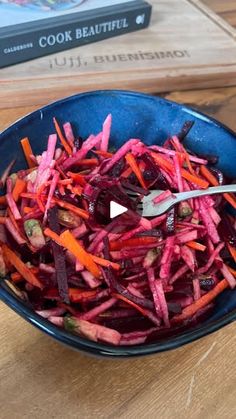 a blue bowl filled with carrots and beets on top of a wooden table