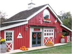 a red barn with pumpkins in the front